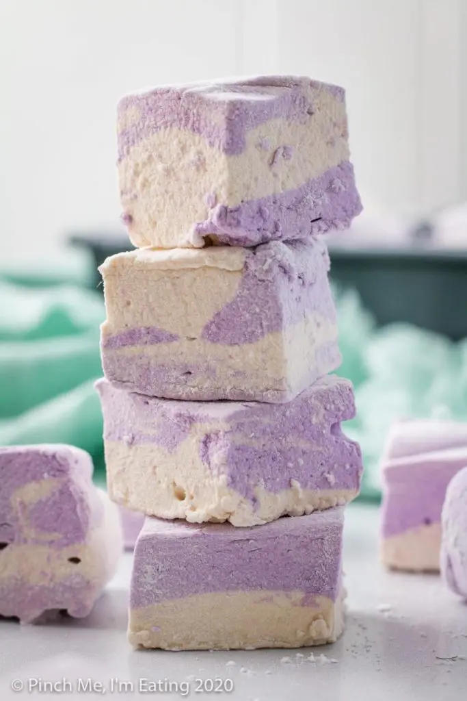 A stack of four purple and white swirled homemade Earl Grey marshmallows with a blurred blue-green napkin in the background