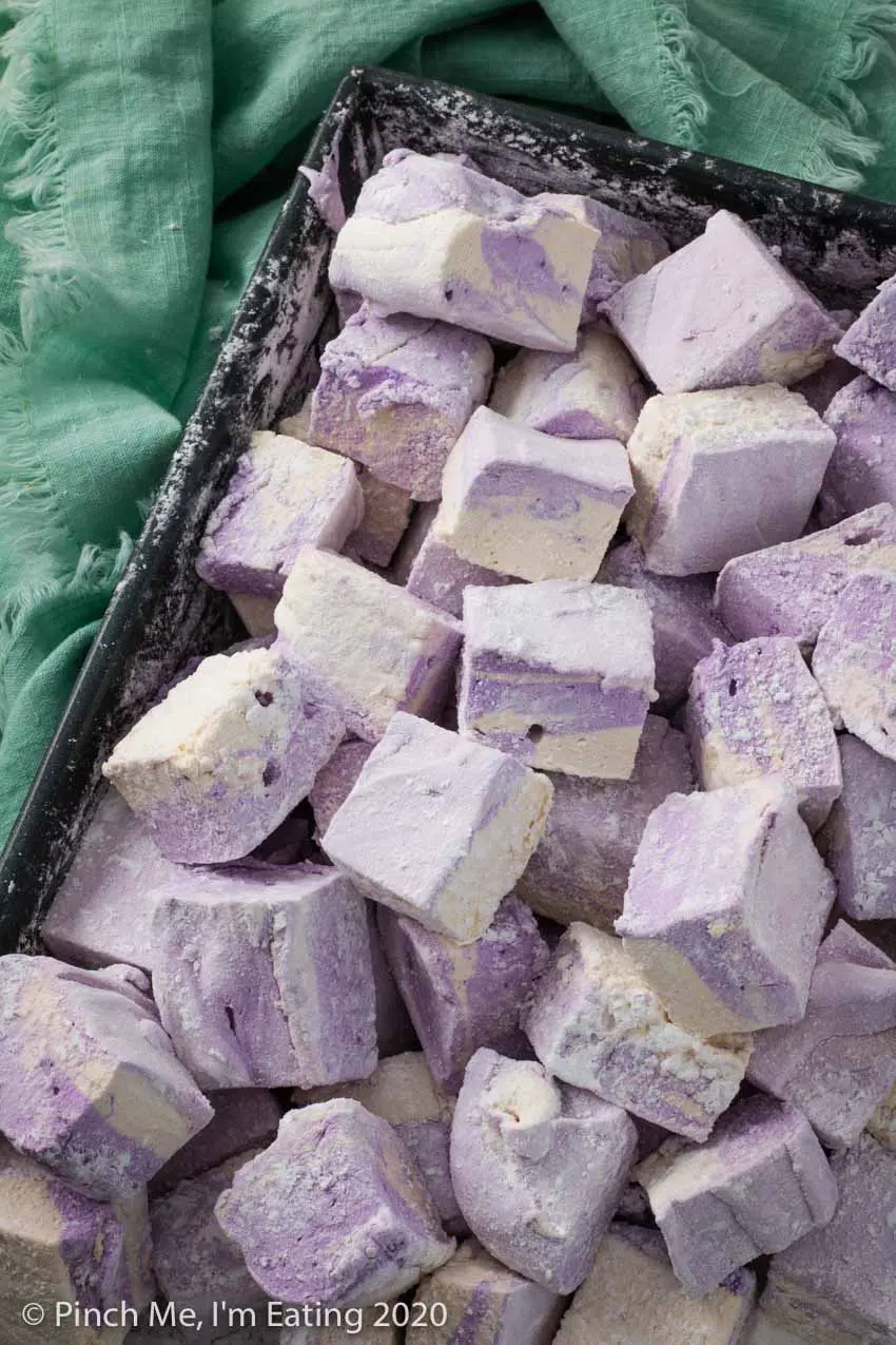 A baking pan full of purple and white swirled homemade Earl Grey marshmallows next to a blue-green fringed napkin 