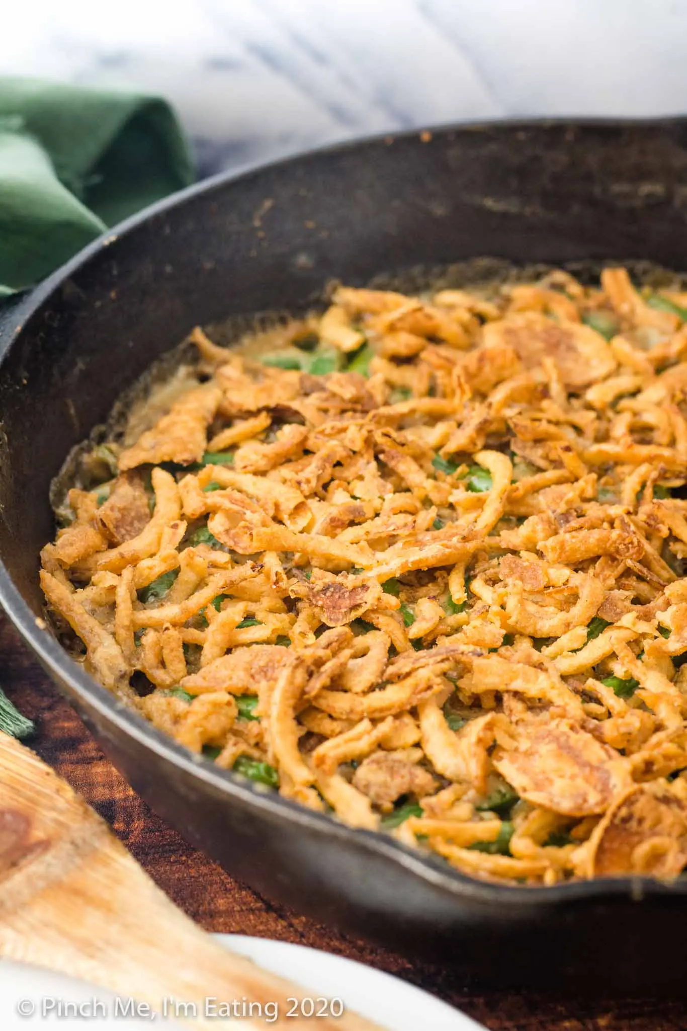 Cast iron skillet full of fresh green bean casserole topped with crispy fried onion topping