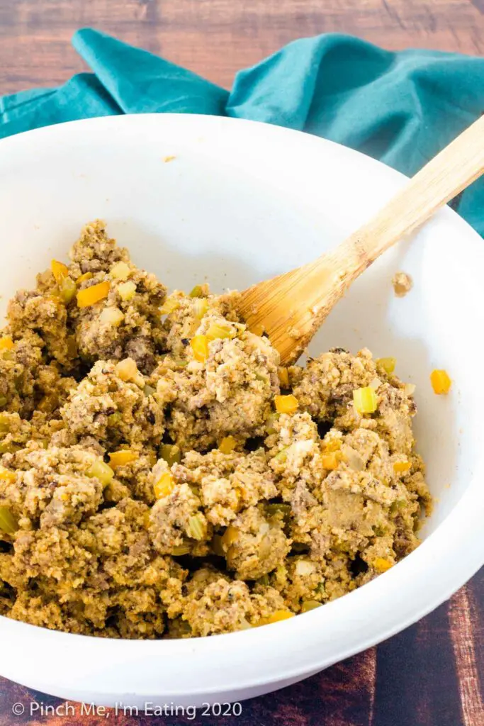 Southern cornbread dressing mixture in a white bowl with a wooden spoon