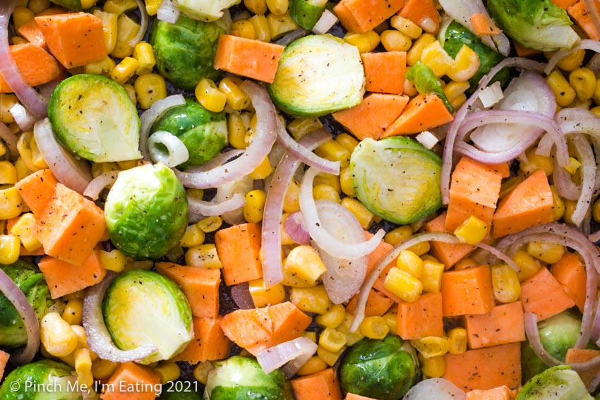Closeup of cut Brussels sprouts, diced sweet potatoes, shallots, and corn