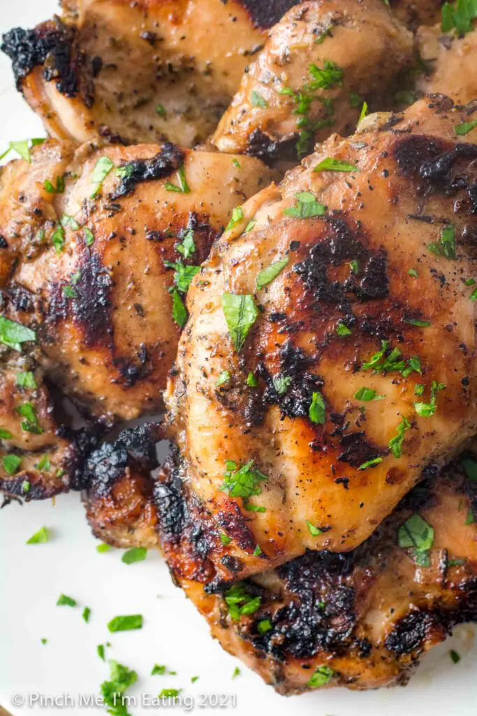 Overhead close up of grilled balsamic marinated chicken thighs topped with bits of parsley 