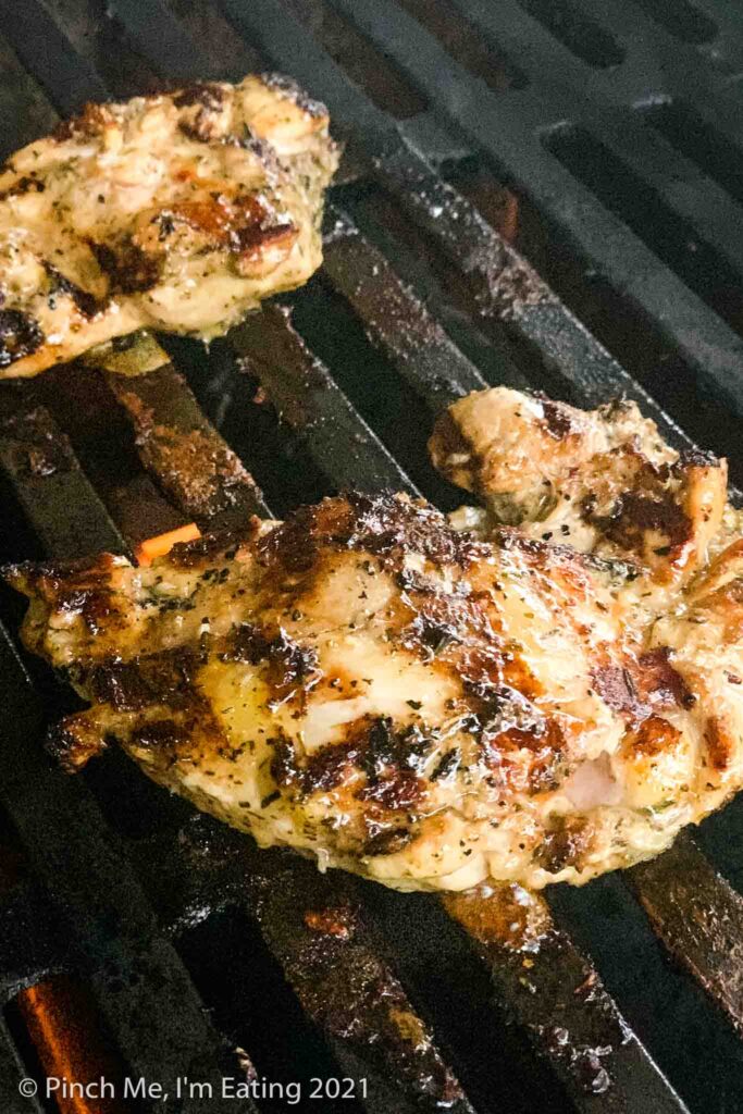 Two balsamic marinated chicken thighs on a grill
