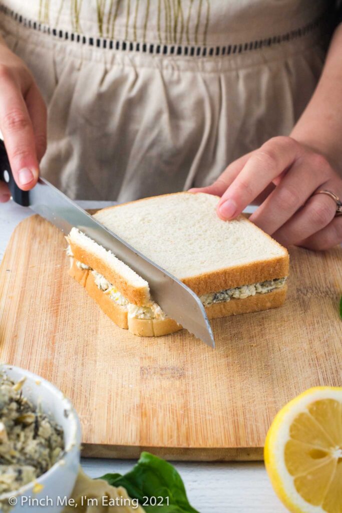 Cutting crusts off sandwich with serrated bread knife