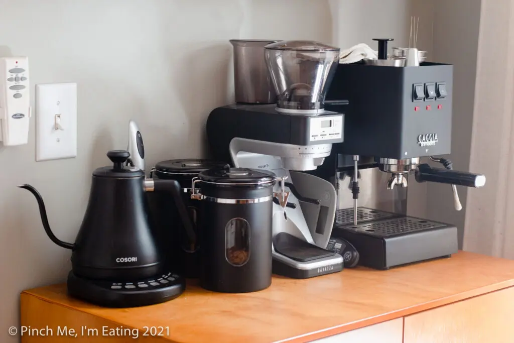 Modern DIY at-home kitchen coffee bar station cabinet with espresso machine, coffee canisters, and electric kettle