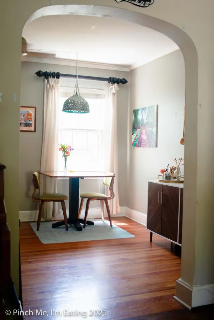 Cafe table in dining room next to window with pendant light and fresh flowers and DIY home coffee bar station on a buffet table