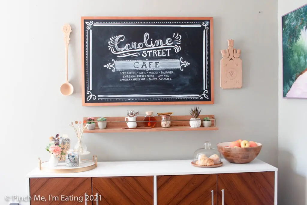 DIY at-home coffee station ideas - coffee bar on dining room buffet with fruit bowl and pastry display, floating shelf, and menu chalkboard