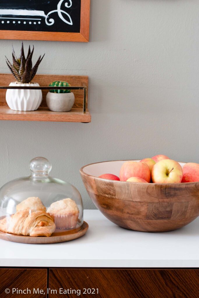 DIY at-home coffee station ideas - coffee bar on dining room buffet with fruit bowl and pastry display, floating shelf, and menu chalkboard