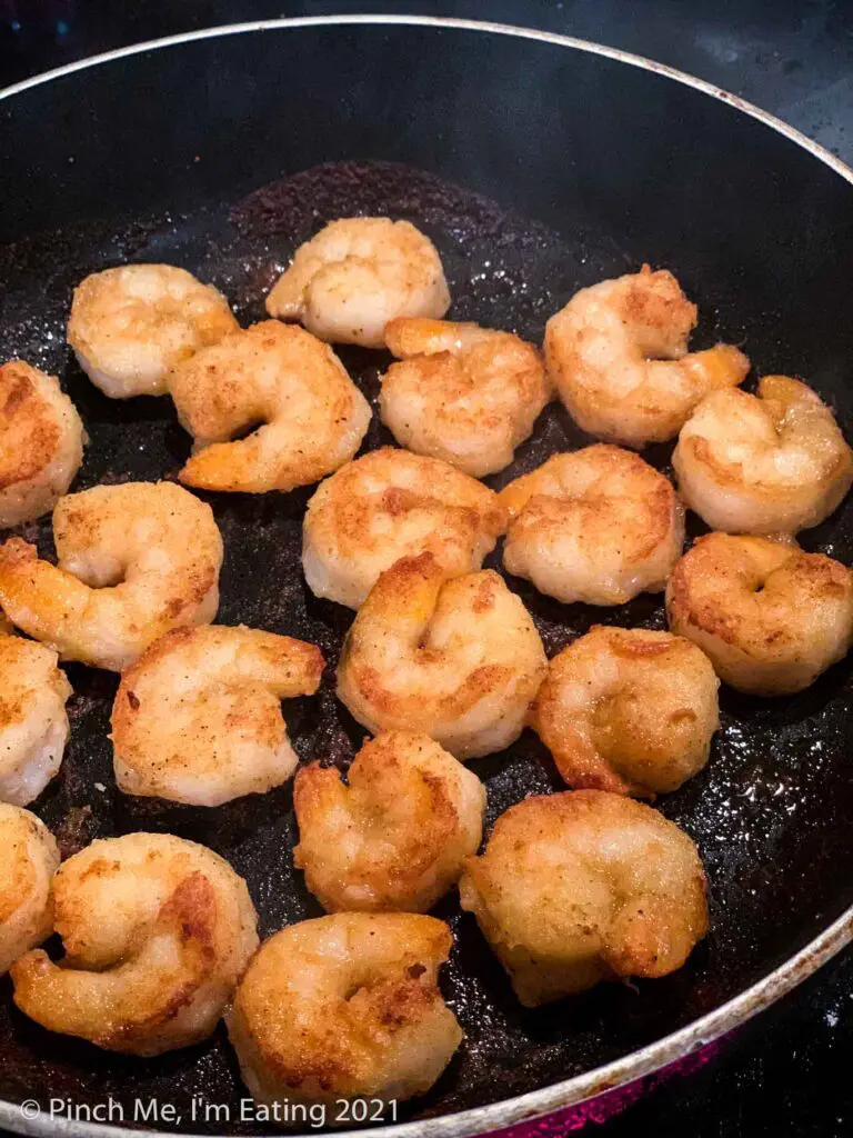 Lightly breaded shrimp frying in a skillet