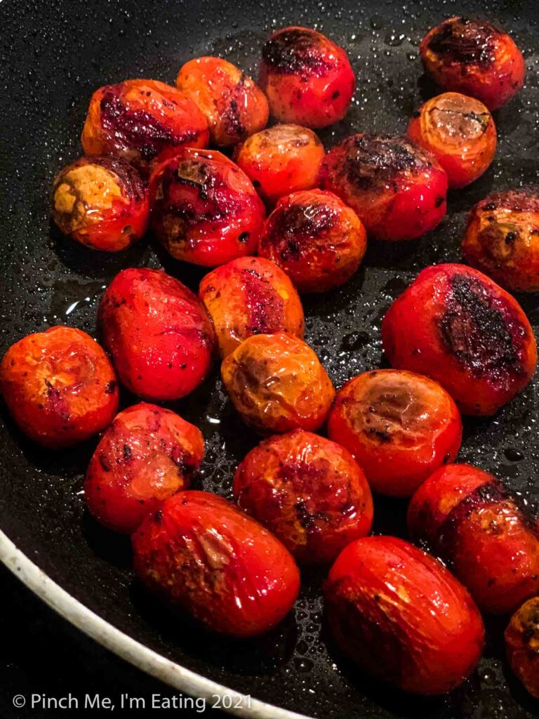Blistered charred grape tomatoes in a black skillet