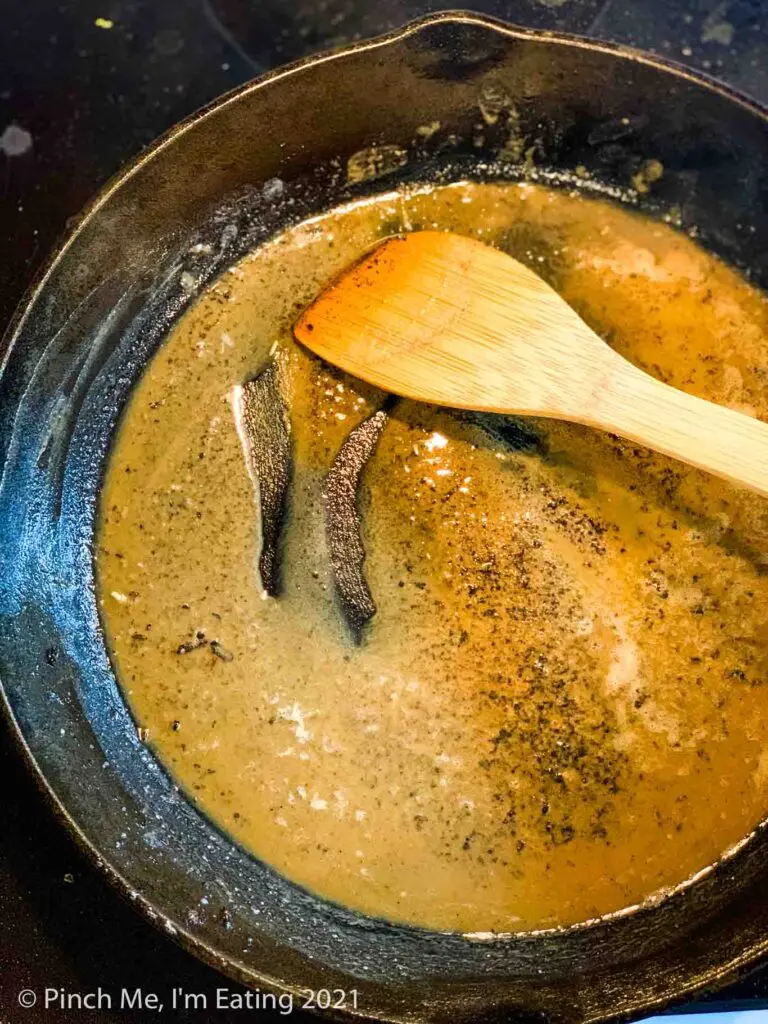 A golden roux of bacon grease and flour in a cast iron skillet with a wooden spoon