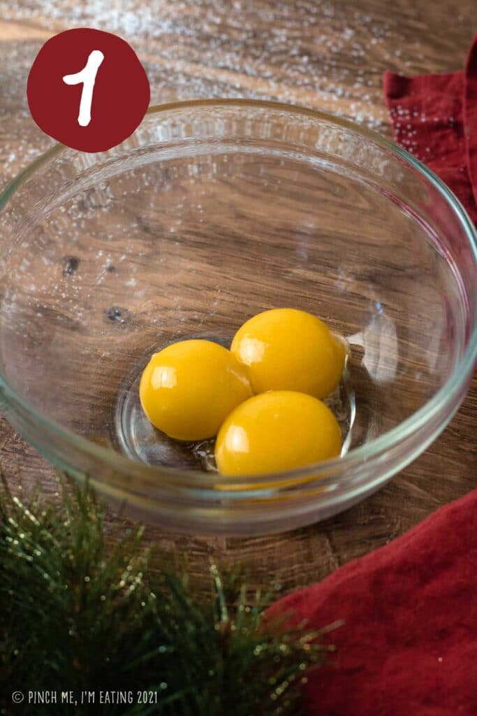 Three egg yolks in a clear bowl.