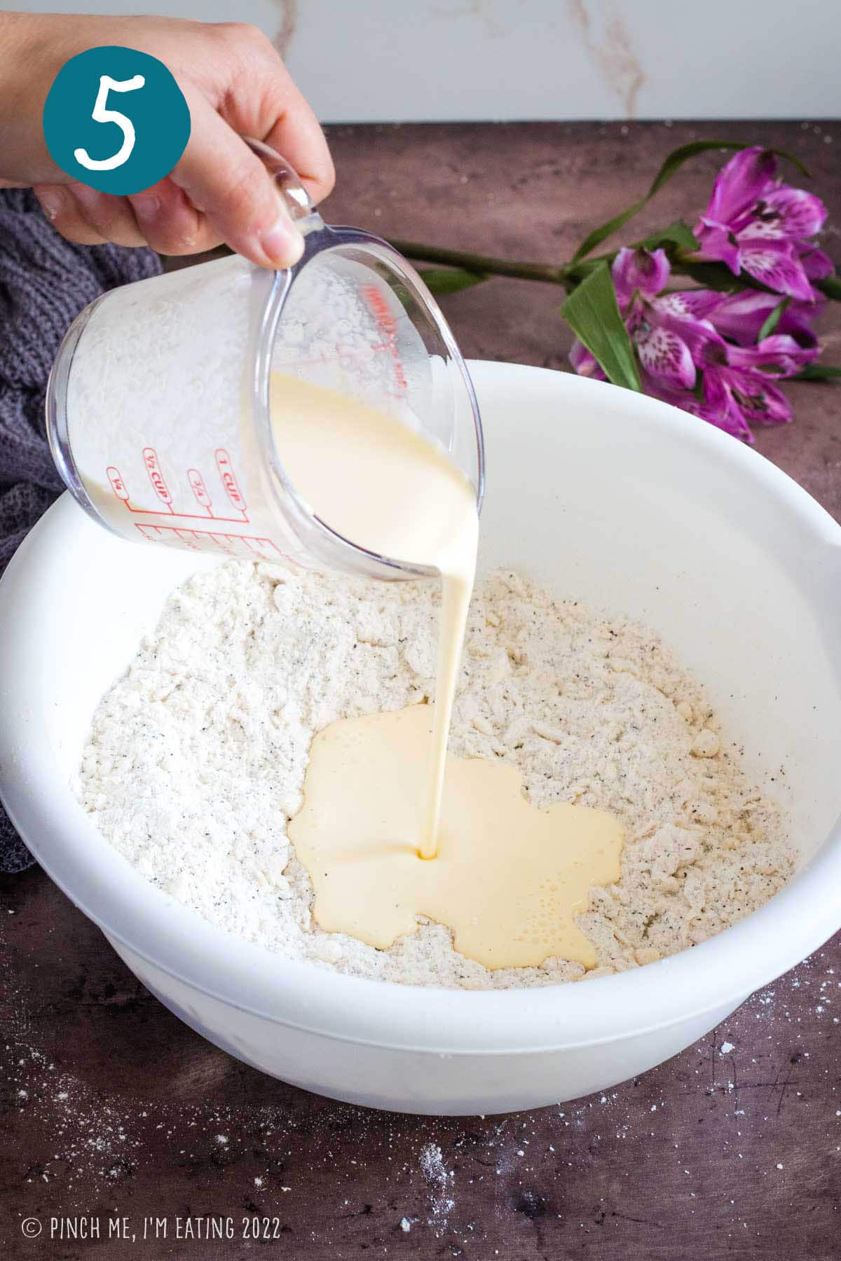 Pouring wet ingredients into flour and butter mixture for scones.