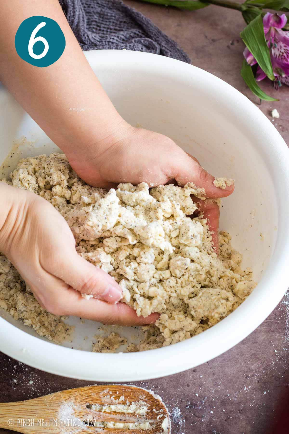 Hands pressing together dough for Earl Grey scones.