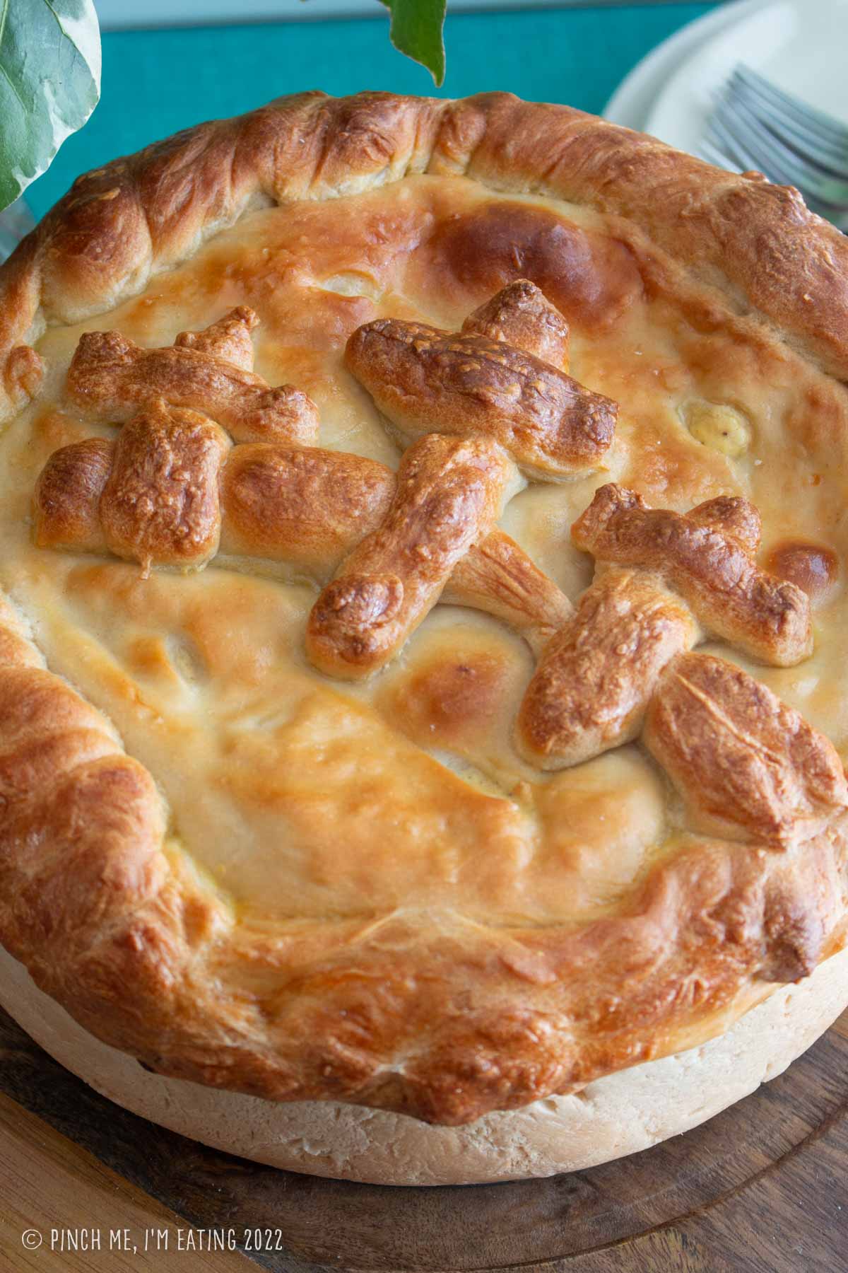 Top of a glossy browned Italian Easter pie decorated with three crosses made of pizza dough.