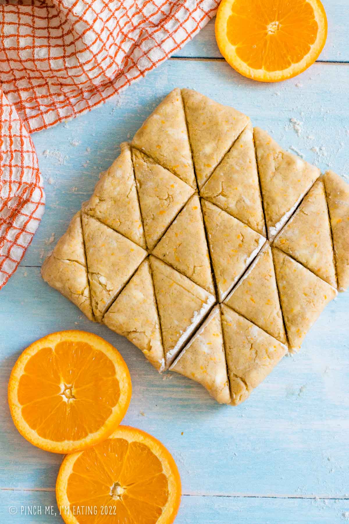 Fresh orange scone dough cut into triangular mini scones.