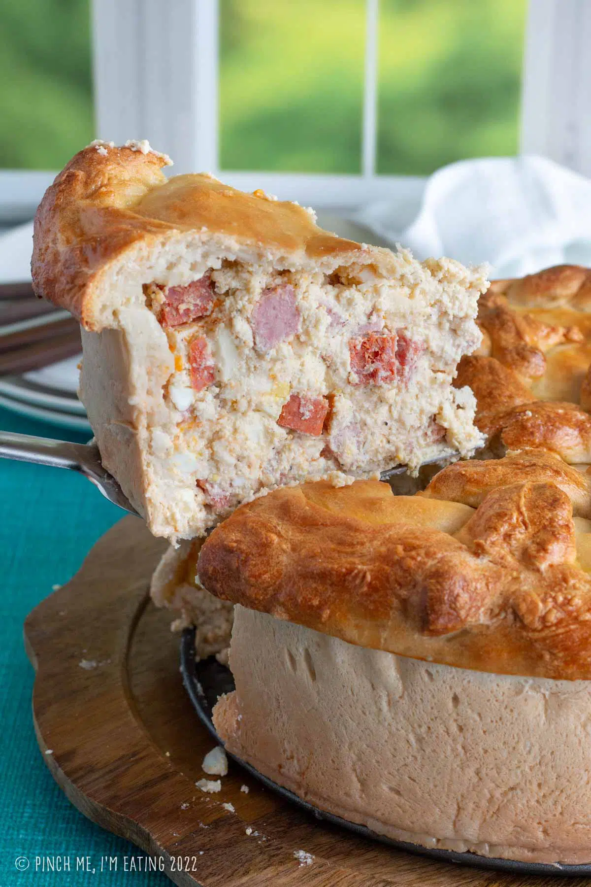 A large slice of pizzagaina being removed from the whole Italian Easter pie.