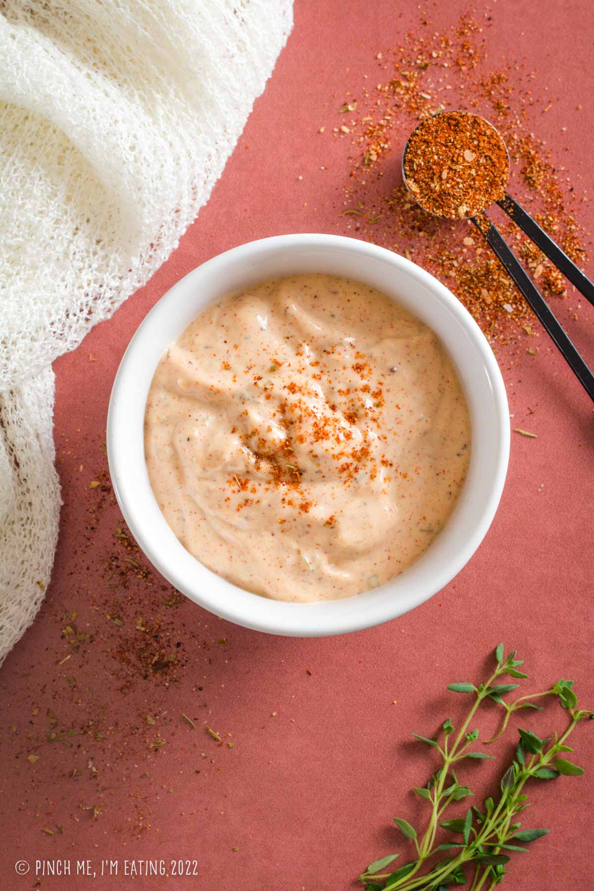 Overhead view of Cajun remoulade in a white bowl garnished with blackened seasoning.