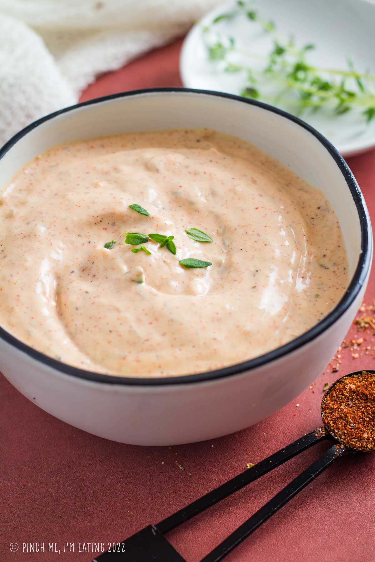 Easy homemade Cajun remoulade sauce in a white bowl garnished with fresh thyme.