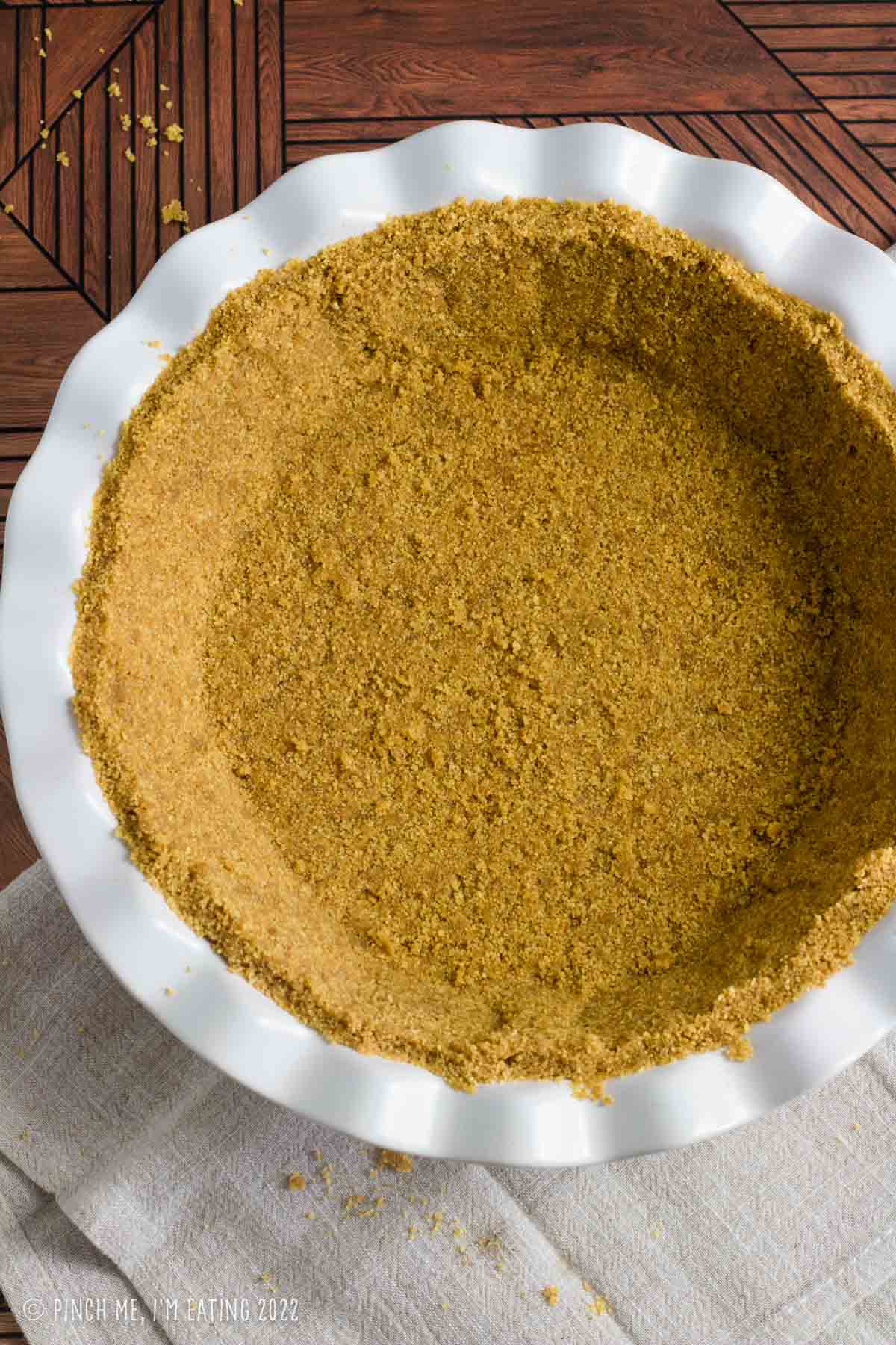 A no-bake graham cracker crust in a white ceramic pie plate.