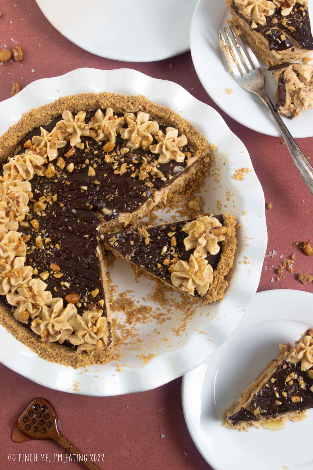 Overhead view of peanut butter pie in a white pie plate with chocolate ganache and crushed peanuts.