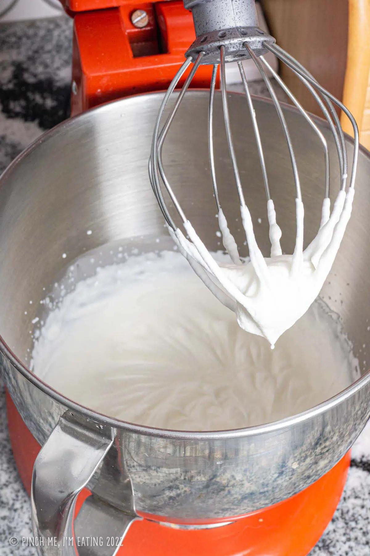 Whipped cream with stiff peaks in a mixing bowl.