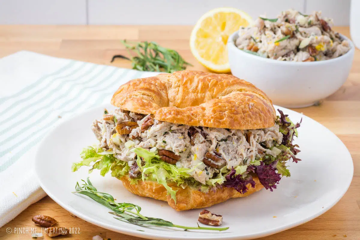 Lemon tarragon shredded chicken salad with pecans and lettuce on a croissant sandwich.
