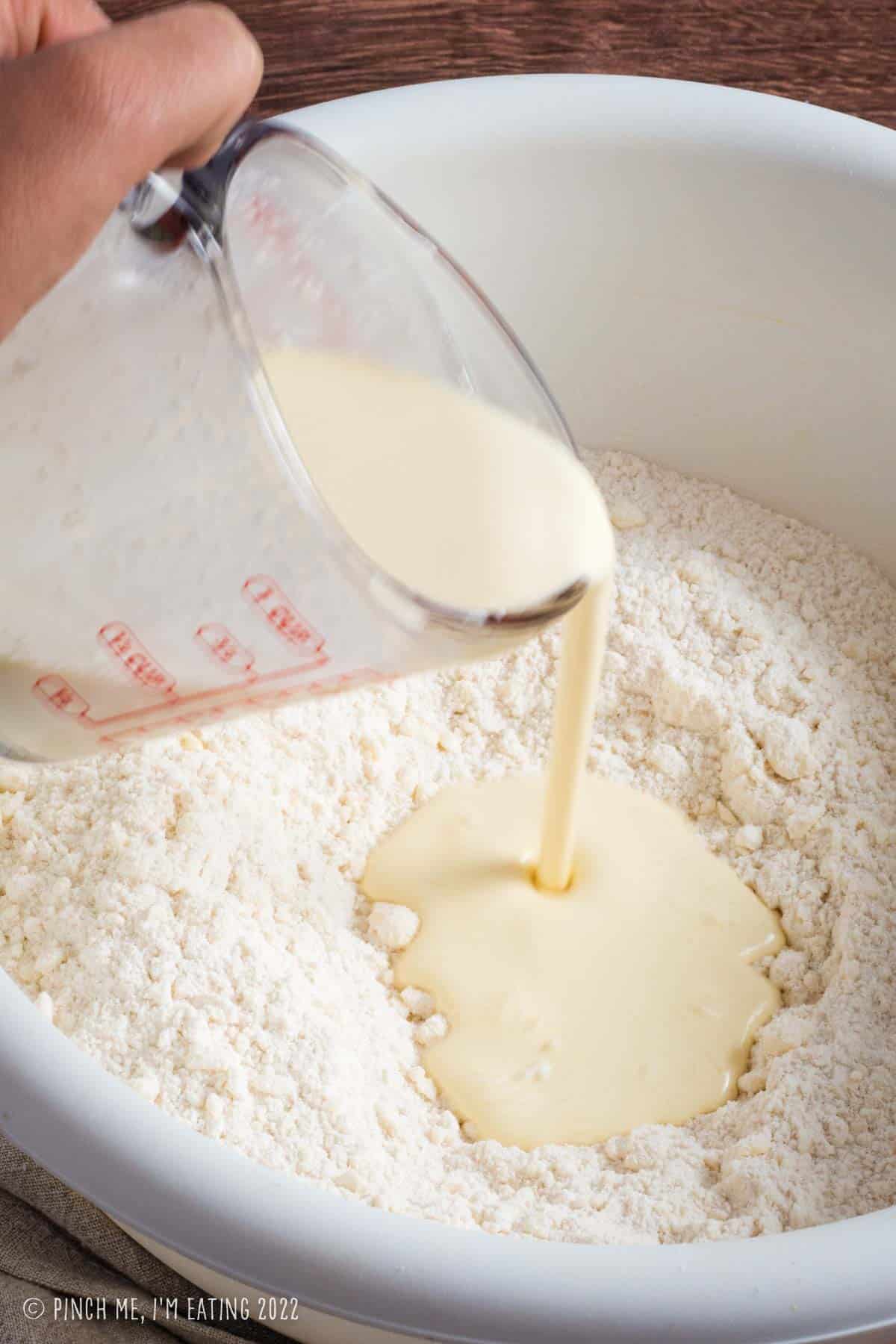 Pouring cream and egg into dry ingredients for scone dough.