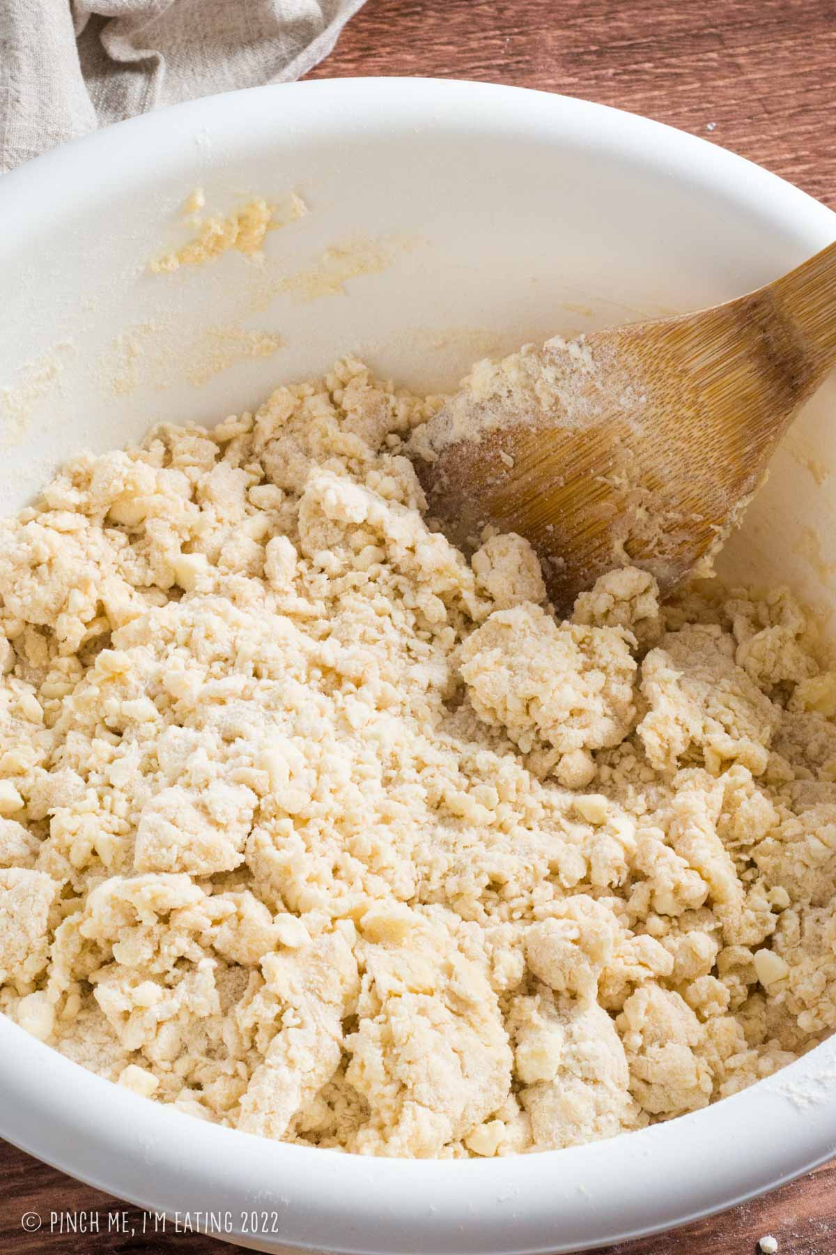 White bowl of shaggy, crumbly basic scone dough.