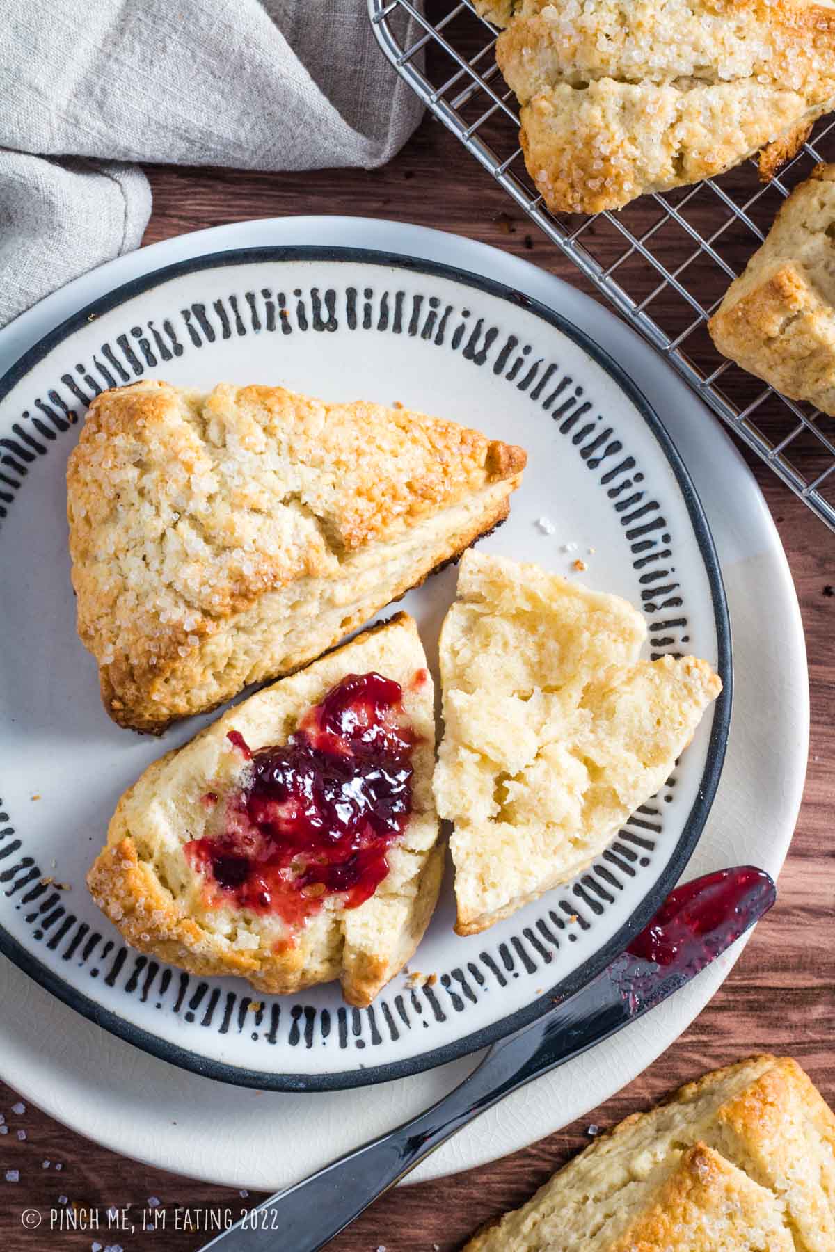 Raspberry jam on a basic scone on a white plate.