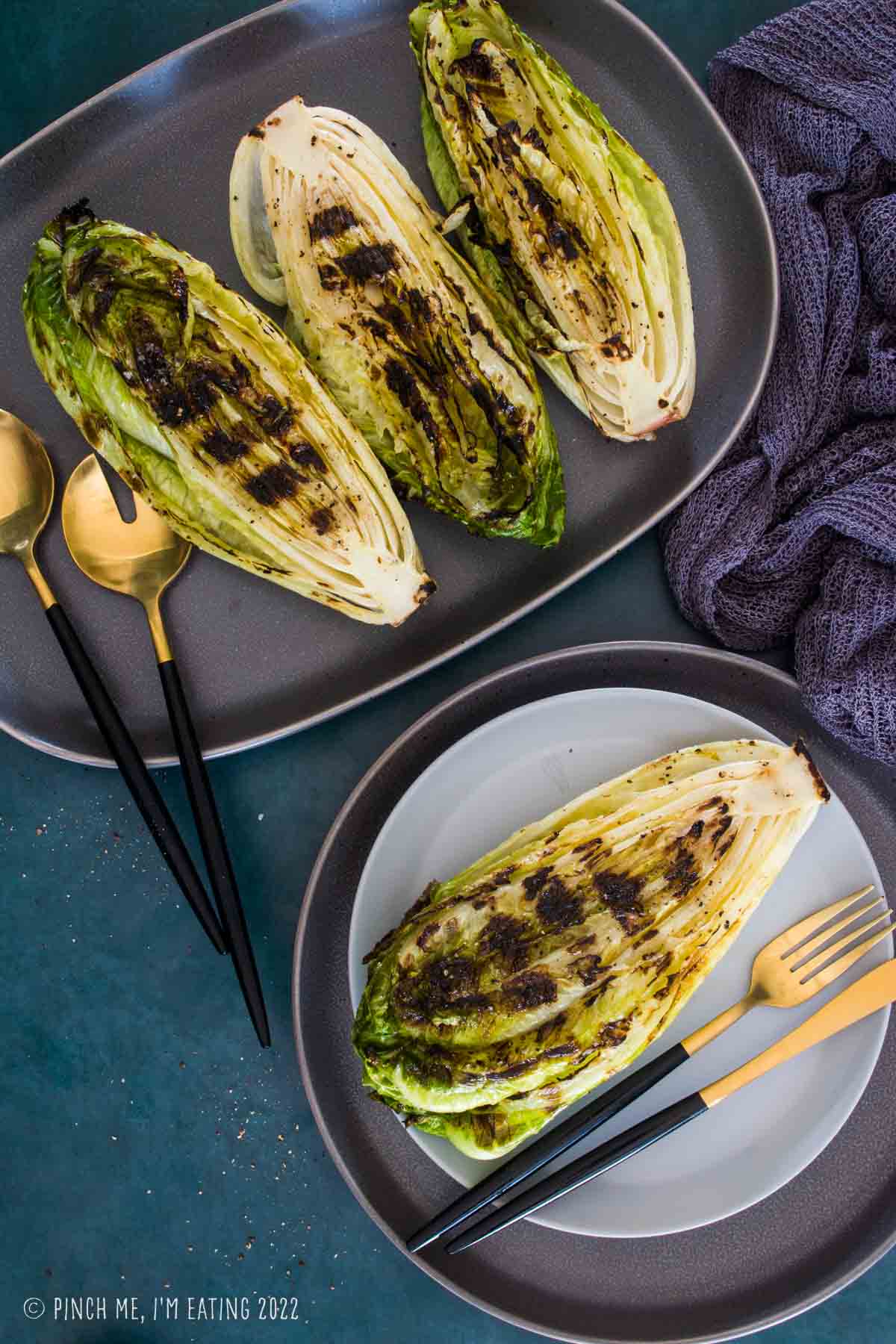 Grilled romaine hearts on serving platter with one on a salad plate.