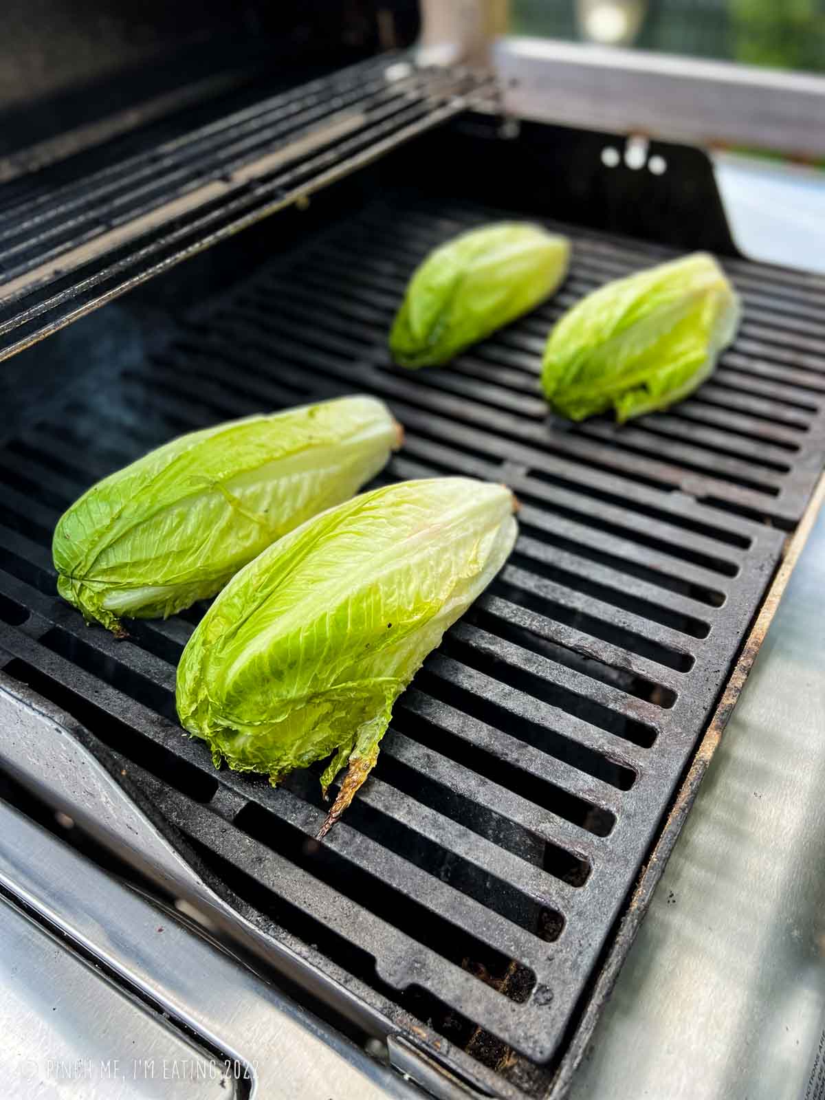 Romaine heart halves cut-side down on a grill.