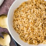 Sesame Hibachi fried rice in a white bowl with gold and black serving utensils.