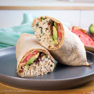 Bacon ranch chicken salad wrap with avocado and tomato on a gray plate.