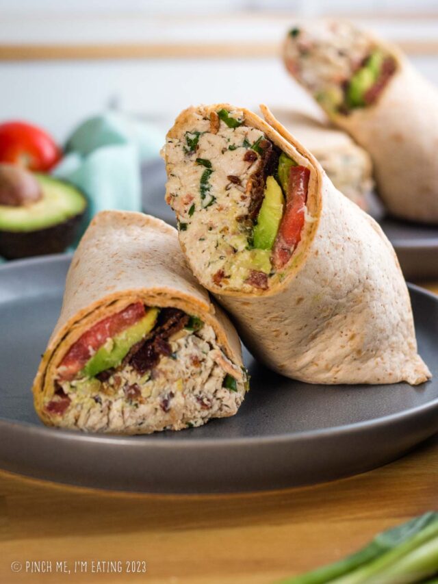 Bacon ranch chicken salad wrap with avocado and tomato on a gray plate.