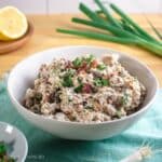 Bacon ranch chicken salad in a white bowl topped with bacon and green onion.