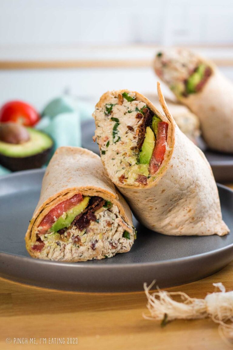 Bacon ranch chicken salad wrap with avocado and tomato on a gray plate.