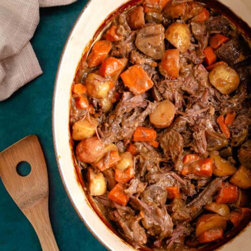 Overhead view of onion soup mix pot roast with carrots and potatoes in a Dutch oven.