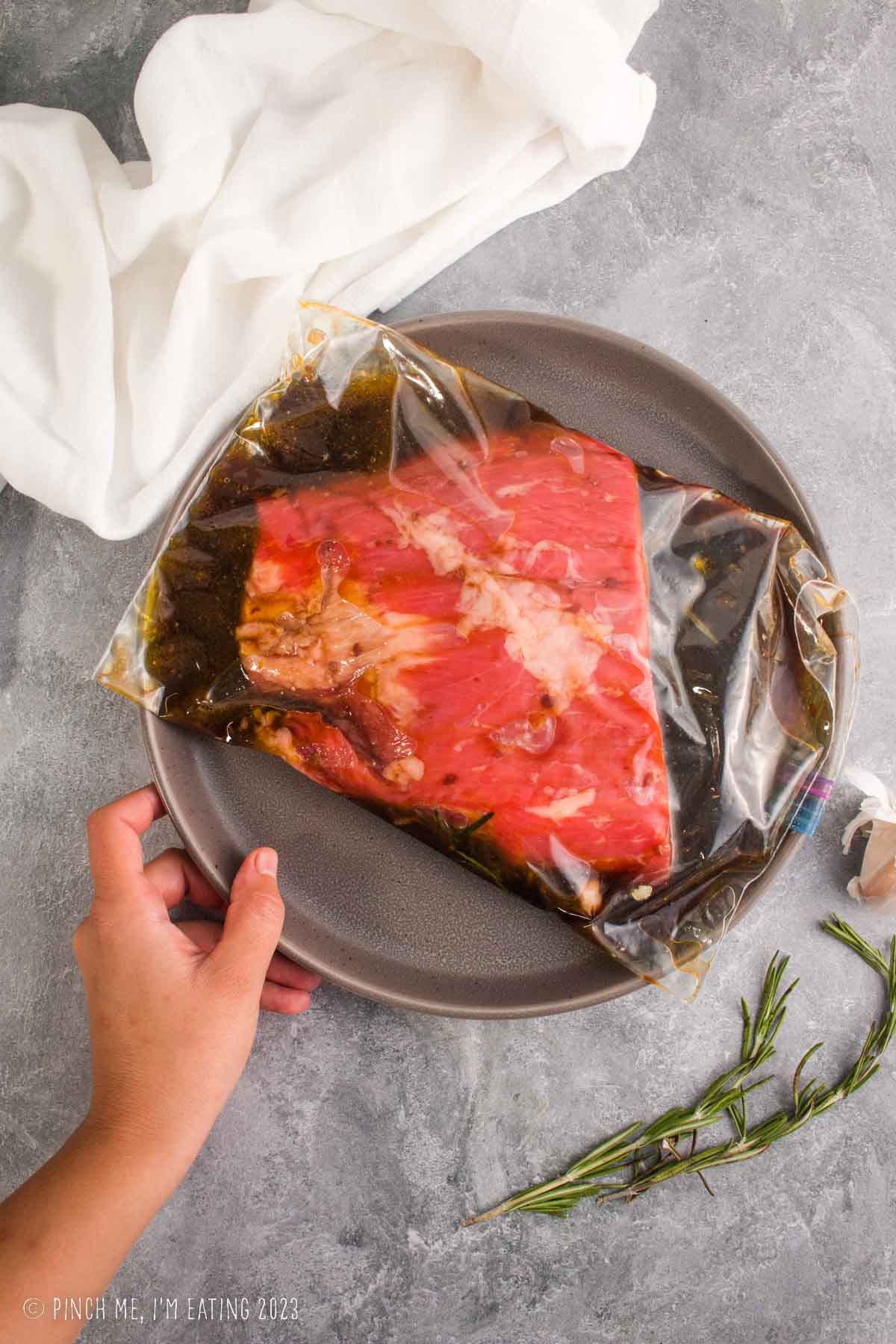 Raw flank steak marinating in a ziplock bag with red wine steak marinade.