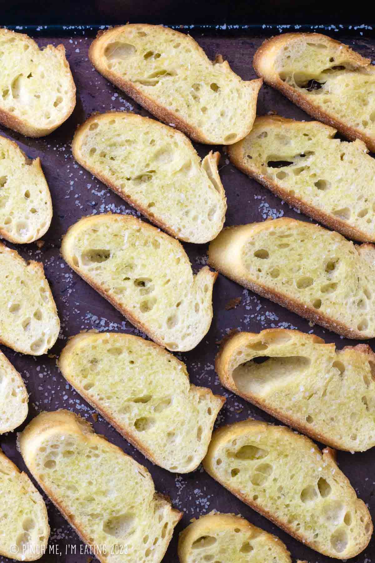 Crostini arranged on a sheet pan.