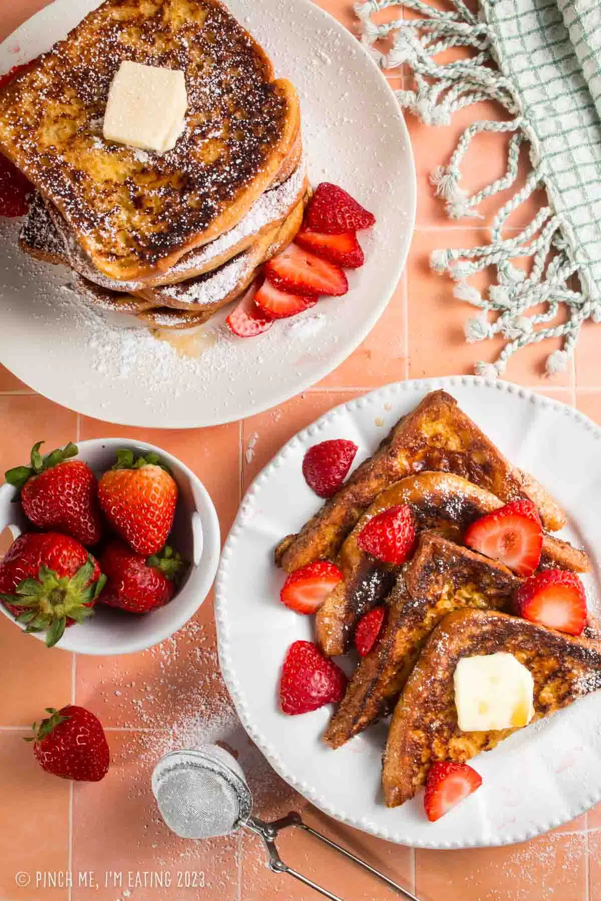Overhead view of brioche French toast with strawberries on white dishes.
