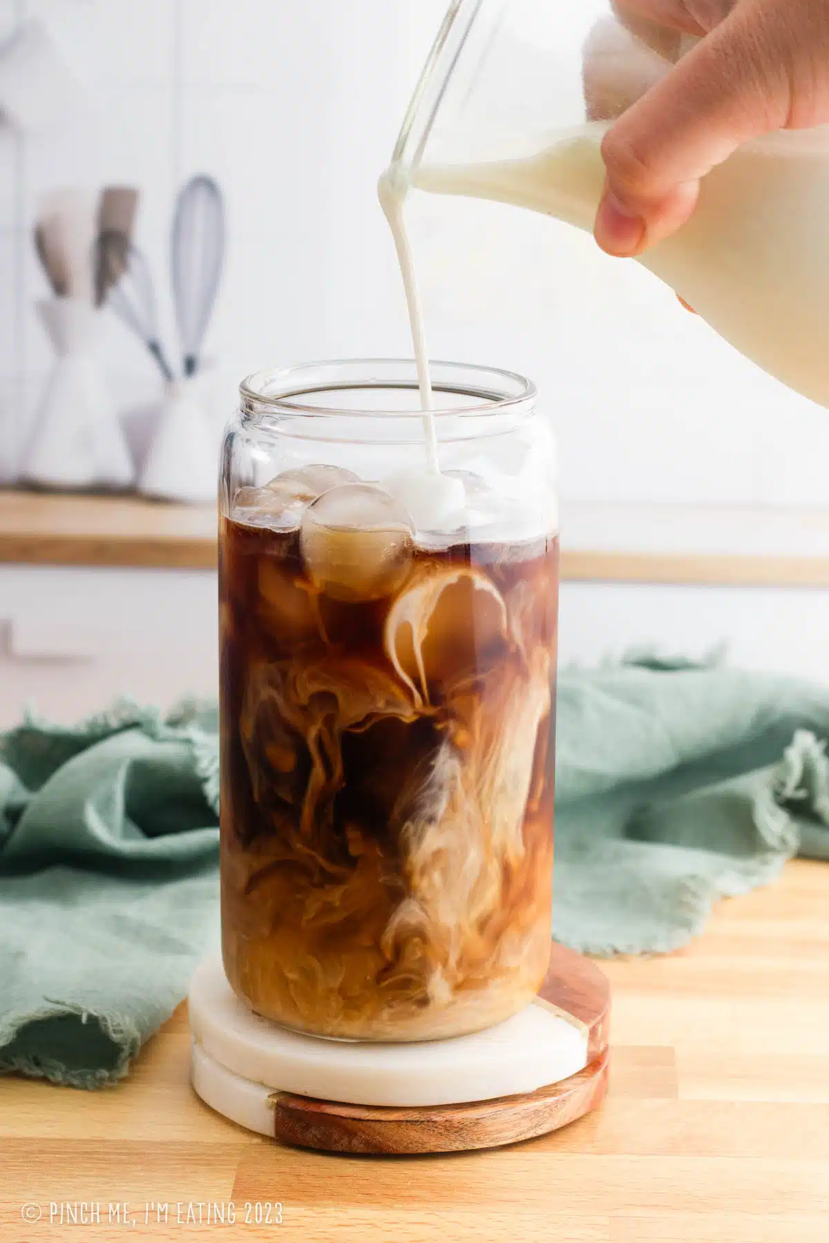 Vanilla sweet cream pouring into cold brew coffee in a tall glass.