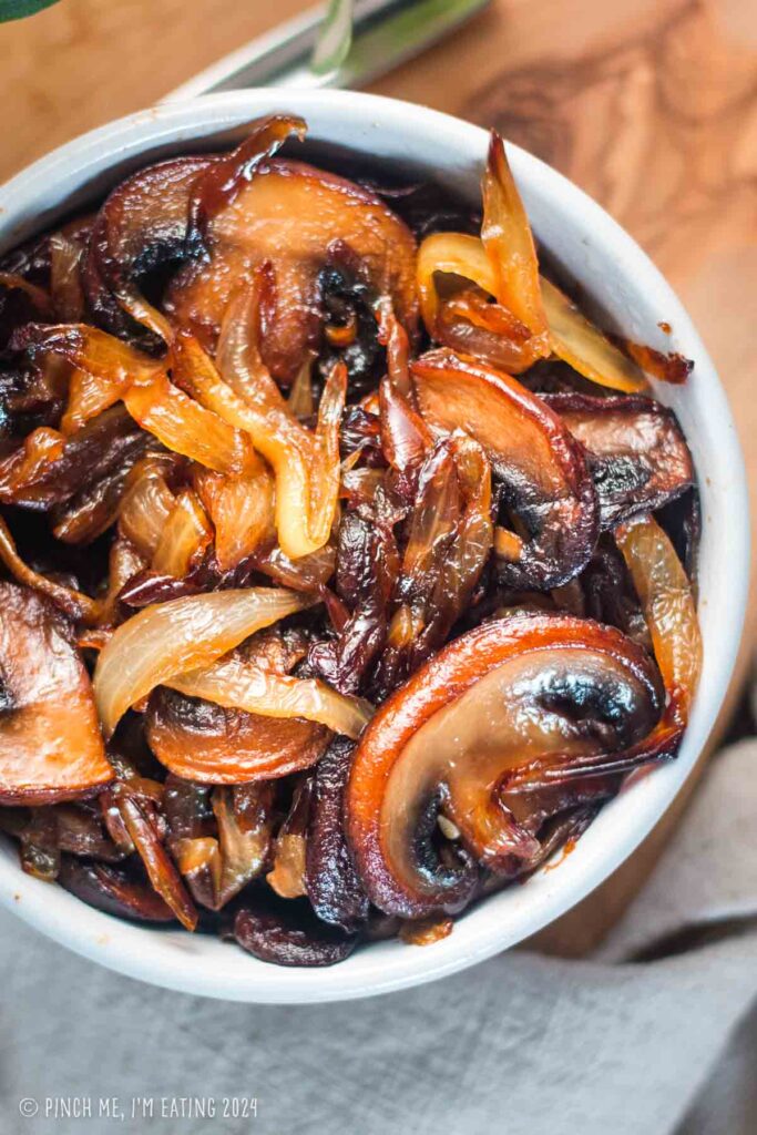 Caramelized onions and mushrooms in a small white bowl.