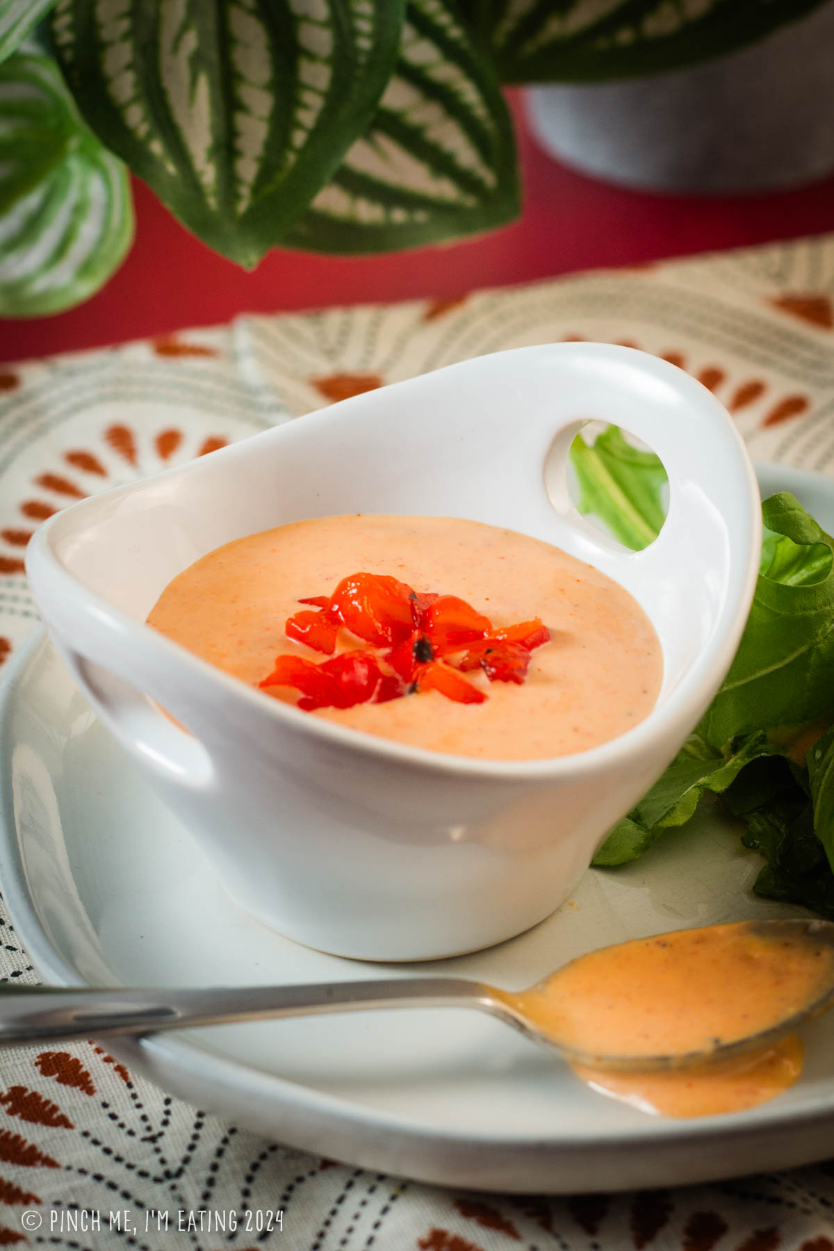 Roasted red pepper aioli in a small white bowl topped with diced roasted bell peppers.