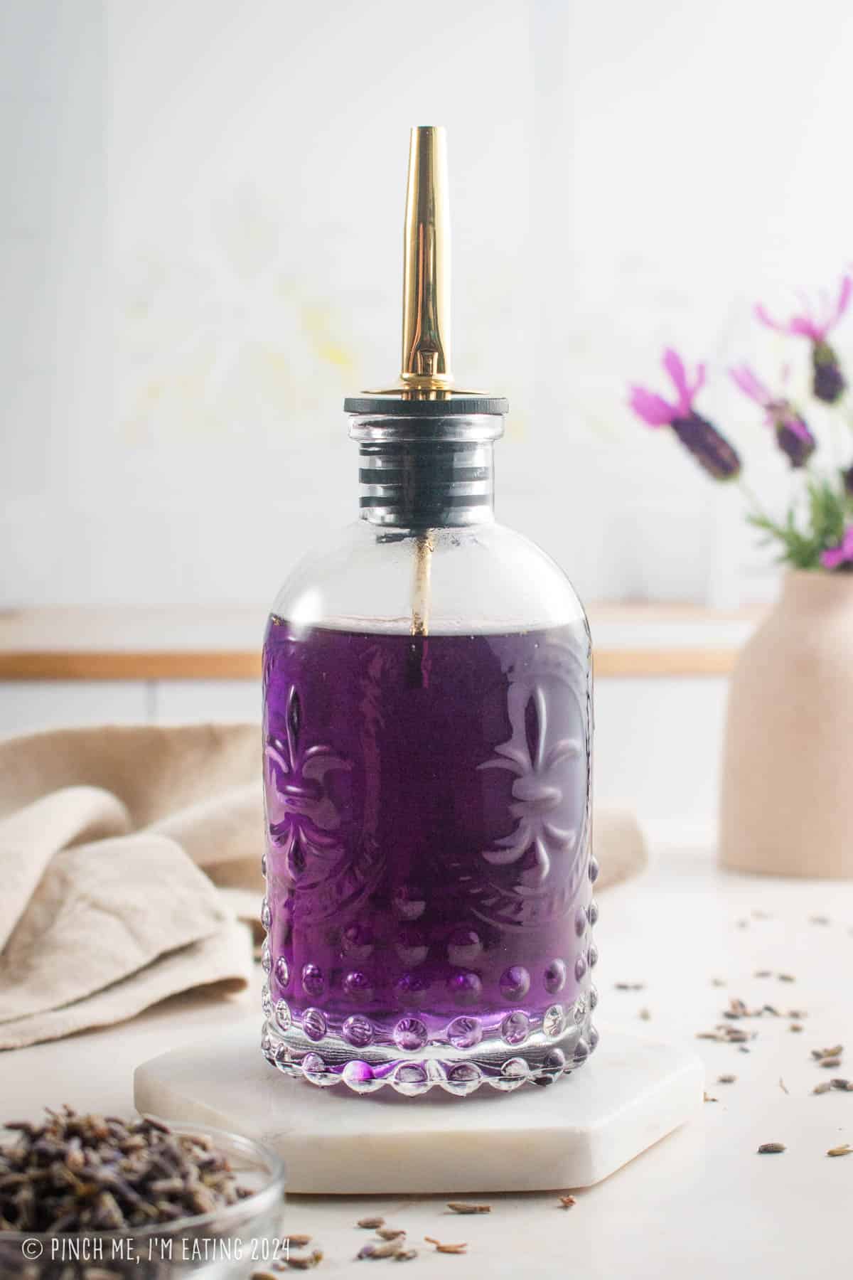 Homemade lavender simple syrup in a decorative glass bottle.