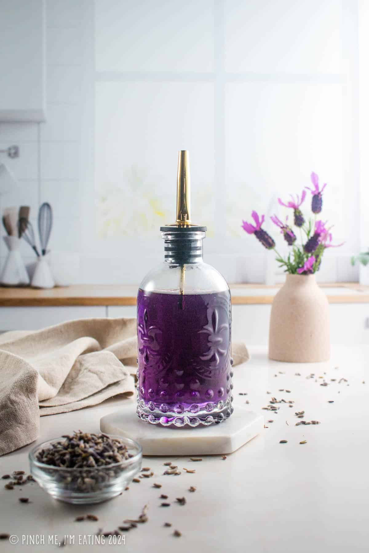 Homemade lavender simple syrup in a decorative glass bottle.
