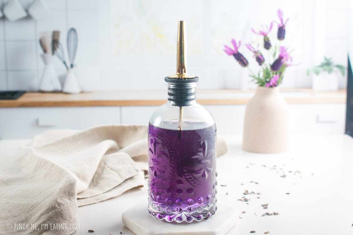 Homemade lavender simple syrup in a decorative glass bottle.