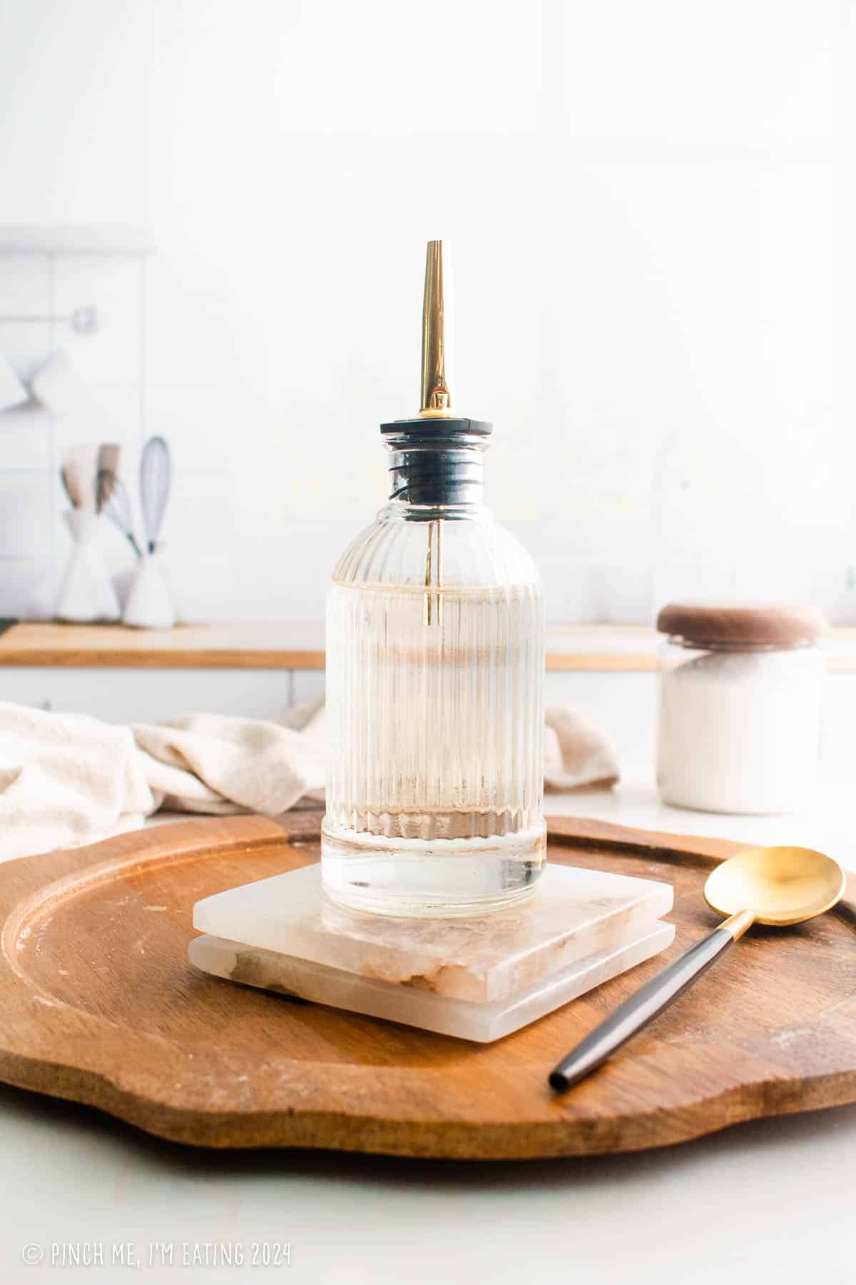 Simple syrup in a glass bottle with a gold spout.