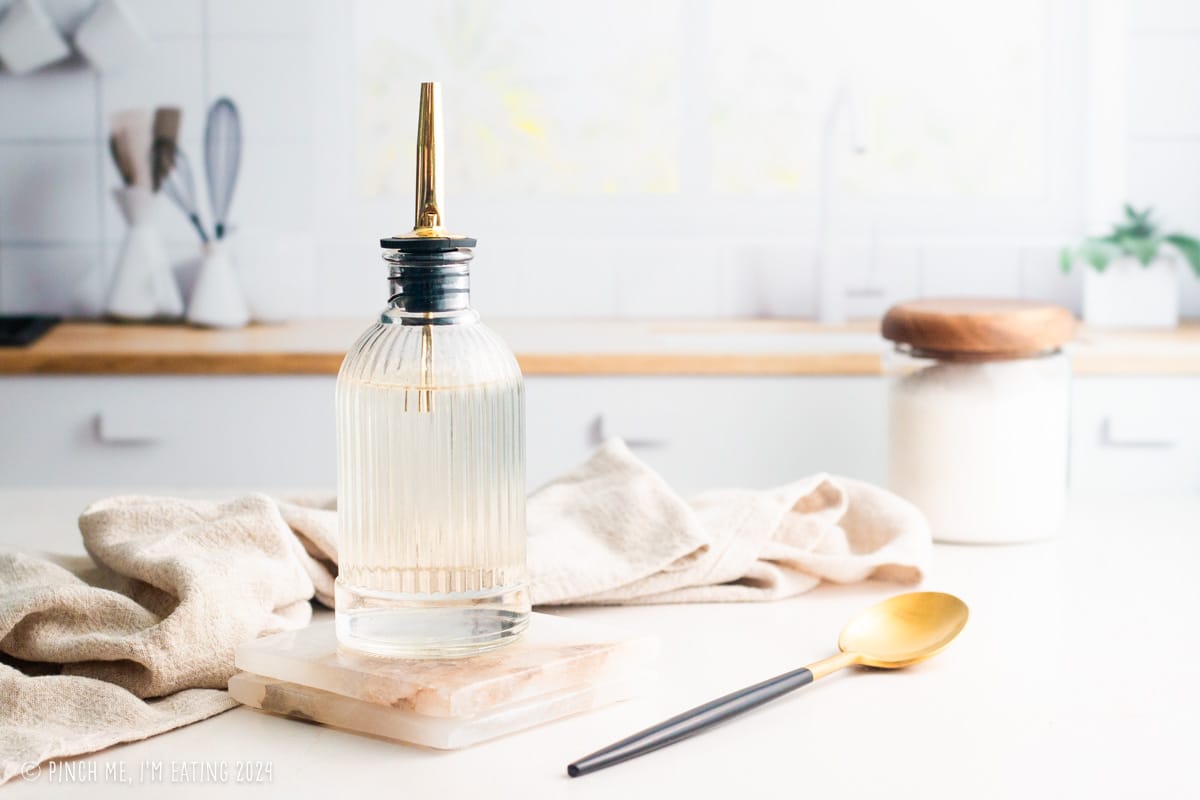 Simple syrup in a glass bottle with a gold spout.