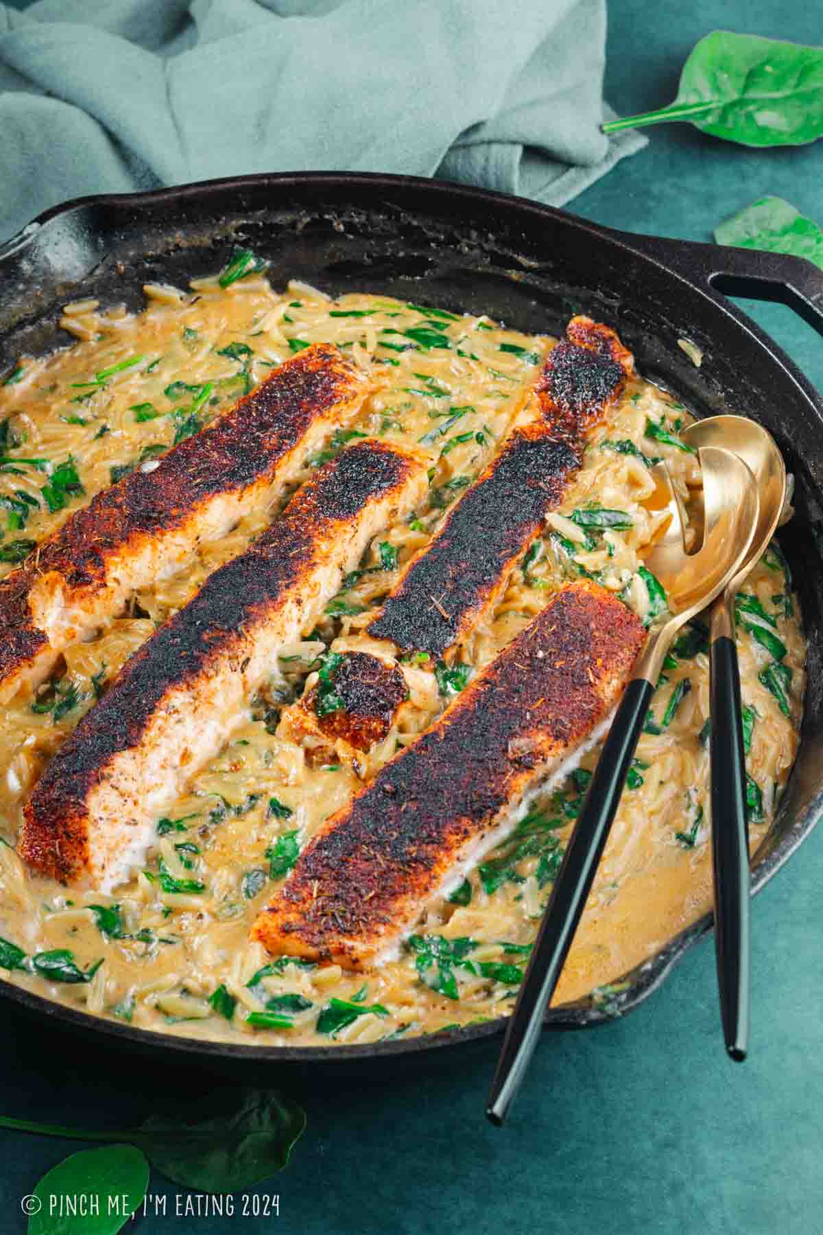 One pan blackened salmon with creamy orzo and spinach in a cast iron skillet.